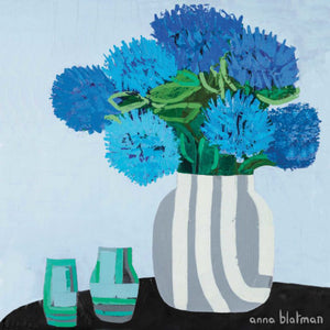 This coaster titled 'Prune' depicts a grey and white vase filled with large vibrant blue flowers, set on a black table with two small vases in shades of green