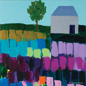 A lonely house and single tree set on a hill with fields of vibrant colours in blues, purples, tan and mint is on this coaster, painted by Anna Blatman and titled Heacham