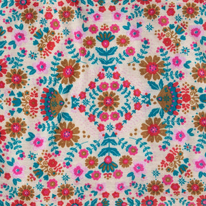 A white background with a print of flowers and leaves in pink, teal and mustard tones