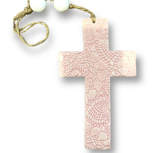 Hand made hanging ceramic wall cross in baby pink with unique intricate pattern imprinted