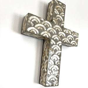 This wall cross from Coast to Coast is solid and super chunky in design with a rainbow pattern in tones of cream